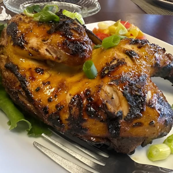 Adobolicious's Filipino-style grilled chicken, glazed and charred, served with fresh greens and salsa.