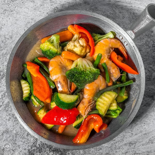 Shrimp and mixed vegetables, including broccoli, carrots, and bell peppers, in a pan.